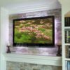 Close-up of wall mounted flat panel TV on stacked stone above fireplace