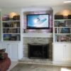 Custom built-in wall unit surrounding fireplace in white