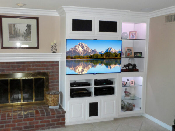 White built-in wall unit modified for flat panel TV, electronic storage, and lighted display space.