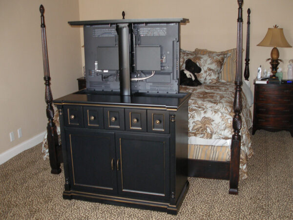 Black motorized TV lift at the foot of the bed. Here the TV faces the bed but could be swiveled.