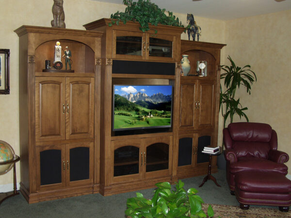 Traditional wall unit with decorative arches, lights, and a flat panel TV mounted to a pull-out articulating wall bracket.