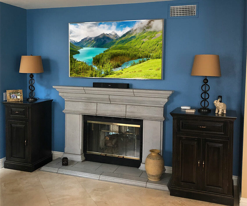 Home Theater Installation with Wall Mounted Flat Panel TV above Fireplace and two custom black audio cabinets