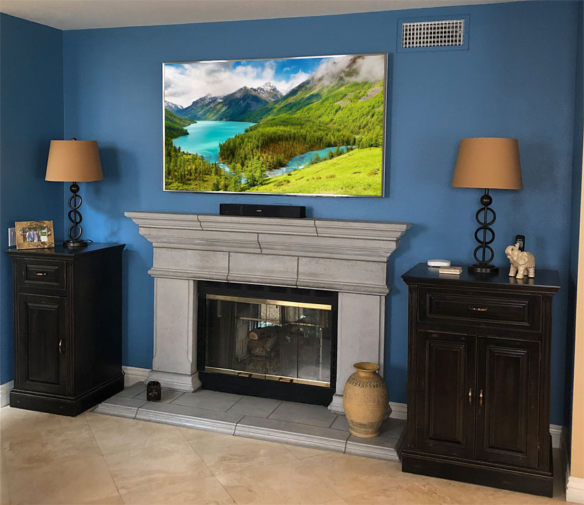 Home Theater Installation with Wall Mounted Flat Panel TV above Fireplace and two custom black audio cabinets